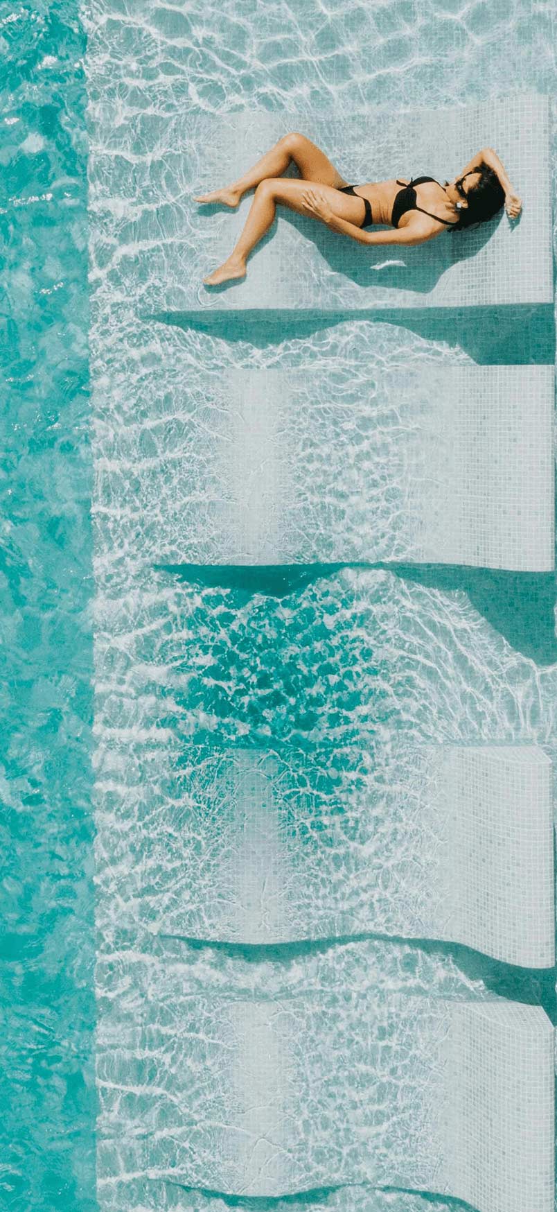 large inground pool with built in tanning ledge with woman laying down