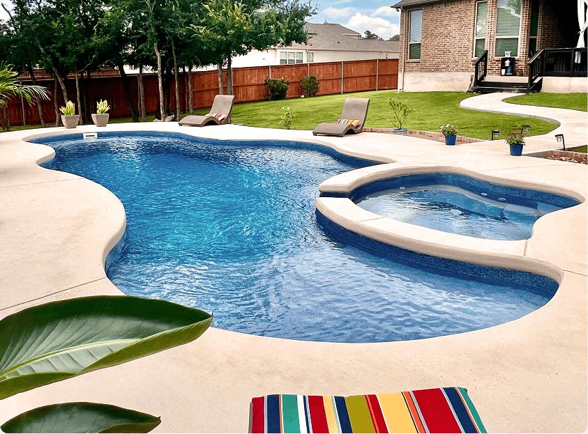 inground swimming pool with spa and light concrete decking
